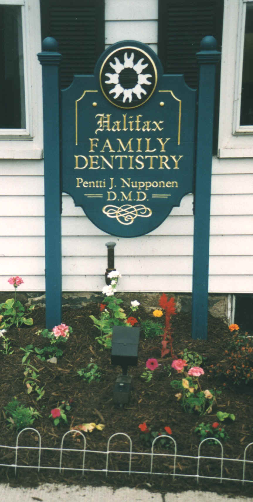 blue and gold carved sign in flower bed